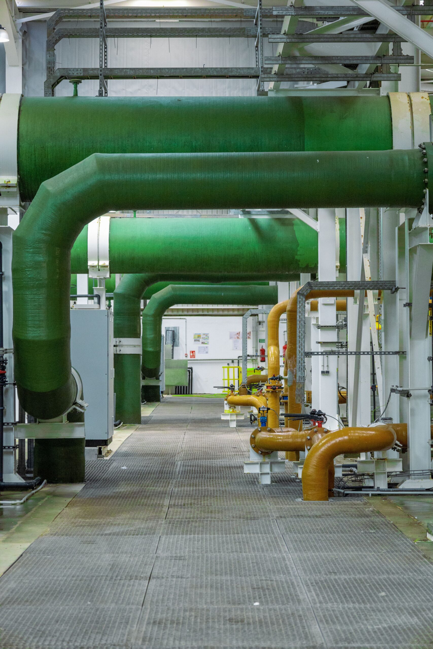 Modern industrial interior featuring green and orange pipelines and technology.