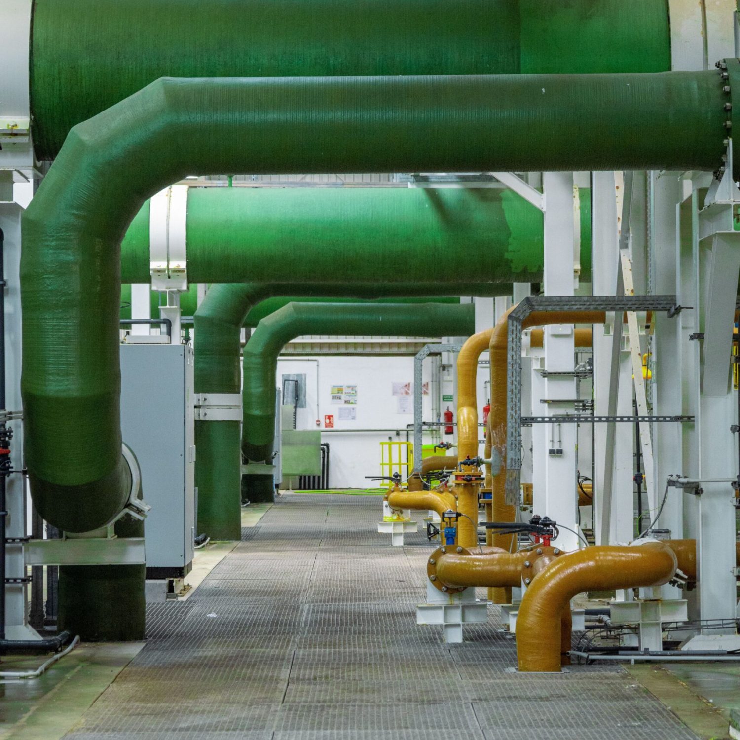 Modern industrial interior featuring green and orange pipelines and technology.